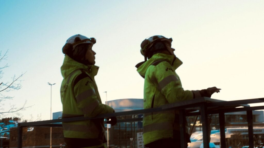 Two workers in hi vis winter jackets looking up at a structure